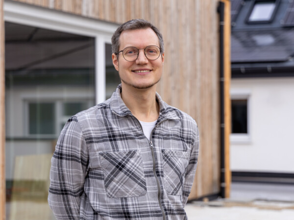 Nicolai Ferchl, Vorstand der Heidelberger Energiegenossenschaft, auf der Dachterrasse des e+KUBATORs vor der Holzfassade des Anbaus.
